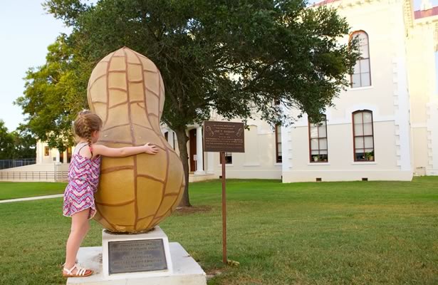 Girl hugging peanut sculpture on Wilson County Courthouse Lawn